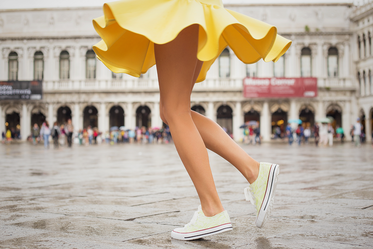 Cheerful young woman wearing sneakers and yellow skirt