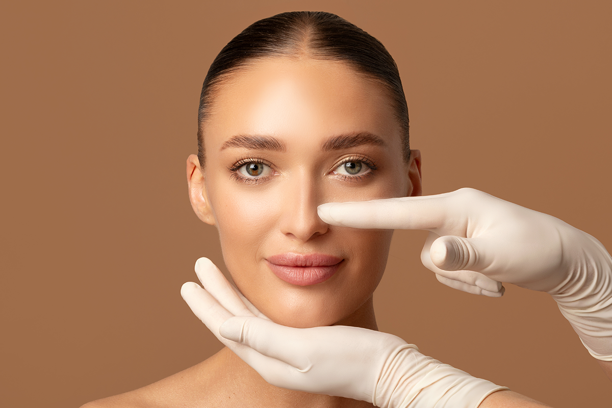 Surgeon hands touching woman nose, examining lady before plastic surgery