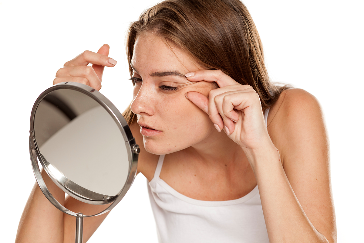 Young woman checking her wrinkles on her eyes