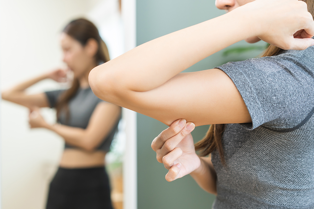 Young woman pinching excess skin on her under arm