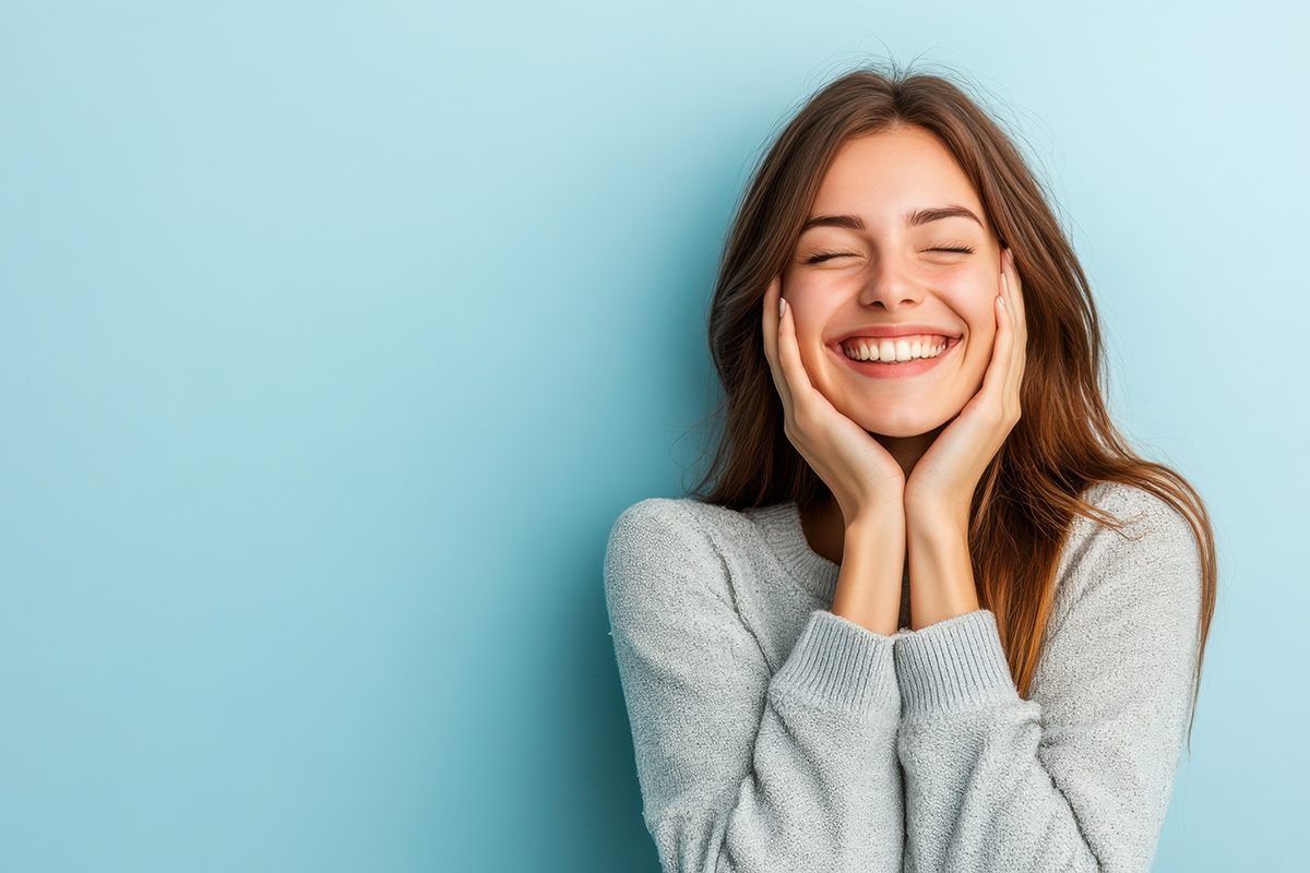 Young woman smiling joyfully with her hands on her cheeks